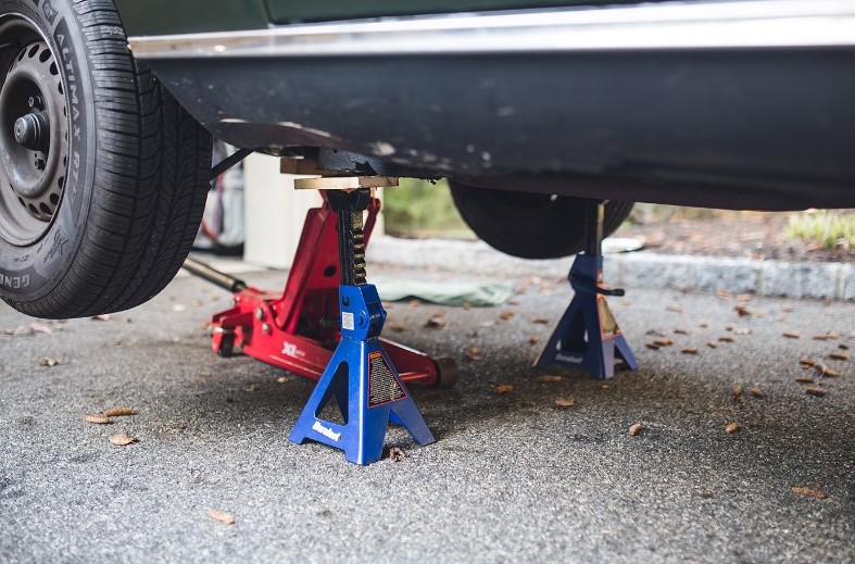 Vehicle lifted on jack stands for oil change.